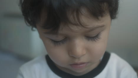 Close-up-portrait-shot-of-little-boy-toddler-looking-down-at-his-hands