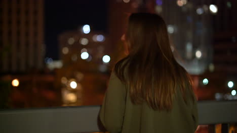 4K-footage-of-woman-overlooking-a-city-at-night