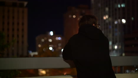 4K-footage-of-man-overlooking-a-city-at-night