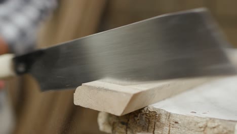 Close-up-of-clean,-large-hand-saw-being-used-to-cut-off-end-piece-of-a-batten