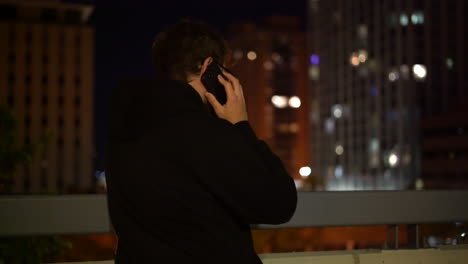 4K-footage-of-male-overlooking-a-city-at-night,-is-lost-and-receives-a-phone-call