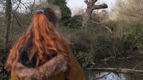 Young-woman-stands-at-a-pond-with-notes-in-her-hand-and-tries-to-discover-the-animals-on-her-records