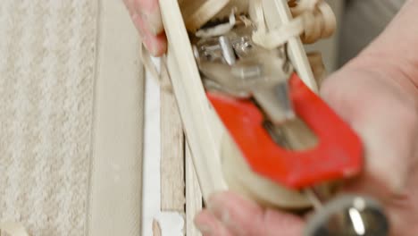 Extreme-close-up-of-carpenter's-hands-leading-plane-over-piece-of-wood,-creating-perfect-wooden-shavings