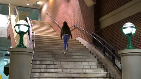 4K-footage-of-woman-walking-up-steps-towards-a-building