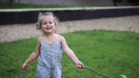 A-little-girl-plays-on-a-meadow-with-green-grass-with-a-dog-toy-tethered-on-a-rope