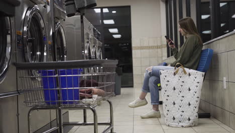 4K-shot-of-girl-sitting-at-al-laundromat-at-night