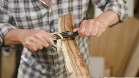 Artisan-in-checkered-shirt-uses-hand-plane-to-form-workpiece-according-to-his-will