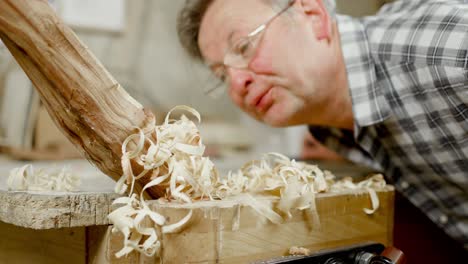 Carpenter-blows-away-pile-of-wood-shavings---sawdust-off-of-workbench