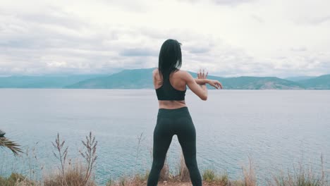 Woman-doing-stretching-exercises-in-front-of-the-sea,-slow-motion