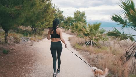 Chica-Trotando-Con-Un-Pequeño-Perro-Blanco-Junto-Al-Mar-En-Cámara-Lenta