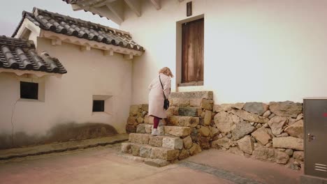 Dame,-Die-Die-Treppe-Im-Himeji-Schloss-In-Japan-Mit-Fallendem-Schnee-Hinaufgeht---Midshot