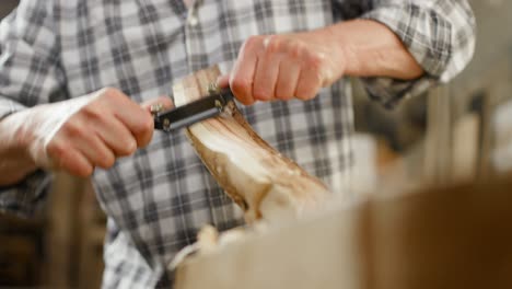 Carpenter-uses-two-handed-plane-to-form-piece-of-wood-after-his-taste