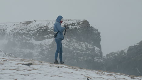 Woman-taking-pictures-in-dramatic-winter-scenery-of-the-Faroe-Islands