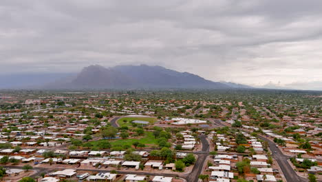 Drone-shot-of-Tucson-Arizona-with-slight-cloud-cover-and-mountains-in-the-distance