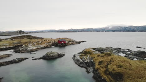Aerial-View-Of-Red-Boathouse-On-Edge-Of-Island-In-Atlantic-Ocean-In-Norway
