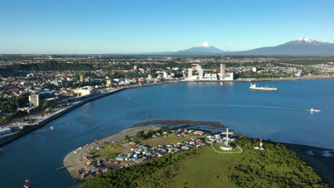 Aerial-Over-Tenglo-Island-With-Bay-Of-Puerto-Montt-With-Calbuco-Volcano-Seen-In-Distant-Background