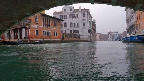 Low-angle-pov-of-boat-passing-under-Ponte-Delle-Guglie-bridge-in-Venice,-Italy-1
