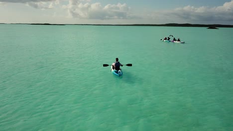 Aerial-Drone-shot-of-a-tourist-riding-a-boat-on-the-coast-of-South-Caicos-surrounded-by-a-blue-and-exotic-Caribbean-sea,-Turks-and-Caicos-Islands-4K