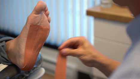 Paediatrician-taping-the-foot-of-a-client-in-a-paediatric-clinic