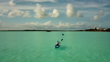 Aerial-Drone-View-of-a-person-riding-a-boat-on-the-coast-of-South-Caicos-surrounded-by-a-blue-and-exotic-Caribbean-sea,-Turks-and-Caicos-Islands