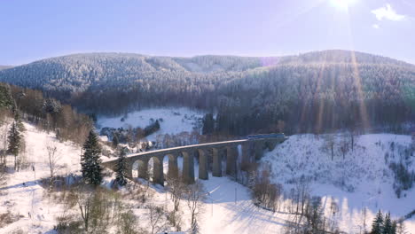 Train-driving-over-a-stone-railway-viaduct-over-a-winter-countryside