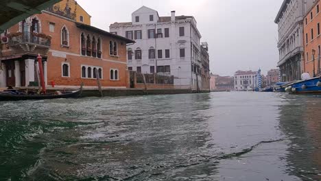 Low-angle-pov-of-boat-passing-under-Ponte-Delle-Guglie-bridge-in-Venice,-Italy