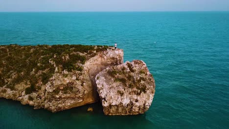 A-man-standing-on-the-peak-of-Cliff-edge-in-the-Turks-and-Caicos-Islands,-Atlantic,-North-America-4K-UHD