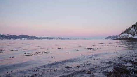 Dirt-Floating-At-The-Beach-Surrounded-With-Snowy-Mountain-In-Indre-Fosen,-Trondelag,-Norway-At-Dusk