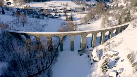 Viaducto-Ferroviario-De-Tren-De-Piedra-Sobre-Un-Pequeño-Pueblo-En-La-Nieve-Del-Invierno