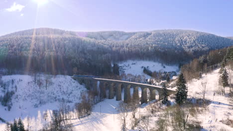 Tren-Cruzando-Un-Viaducto-Ferroviario-De-Piedra,-De-Izquierda-A-Derecha,-Paisaje-Invernal