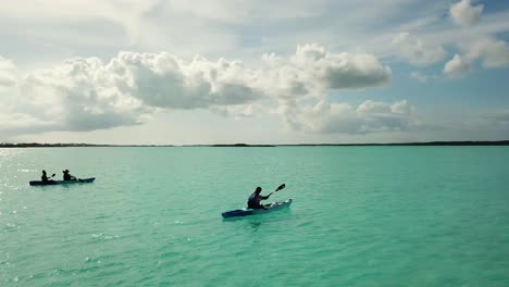 Aerial-Drone-shot-of-a-person-riding-a-boat-on-the-coast-of-South-Caicos-surrounded-by-a-blue-and-exotic-Caribbean-sea,-Turks-and-Caicos-Islands-4K-UHD