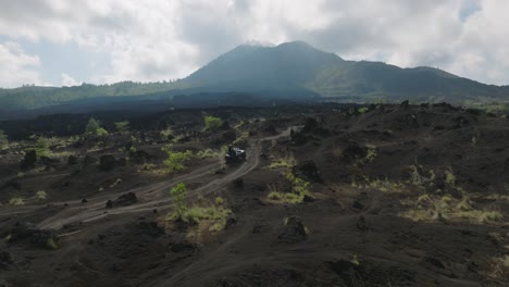 Tourist-Steht-Im-Offenen-Jeep-Und-Fährt-Durch-ödes-Vulkanisches-Lavafeld-Unterhalb-Des-Mount-Batur
