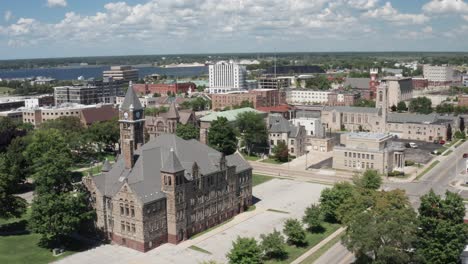 Hackley-Administration-building-in-Muskegon,-Michigan-with-downtown-skyline-with-drone-video-moving-forward