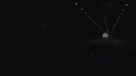 Car-driving-through-a-dark-tunnel-with-bright-daylight-at-the-end-of-it