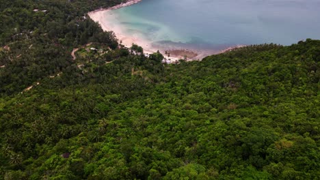 Beautiful-tropical-beach,-cloudy-sky,-and-mountainside-vista-seen-from-above-in-this-aerial-drone-video-taken-over-Koh-Phangan-in-Surat-Thani,-Thailand