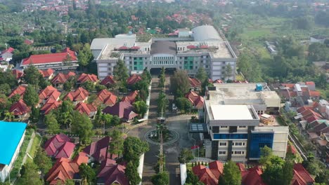 Large-university-campus-surrounded-by-Indonesian-homes-in-Bandung-at-sunrise,-aerial