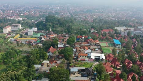Hazy-sunrise-morning-skyline-over-homes-in-Bandung-Indonesia,-aerial