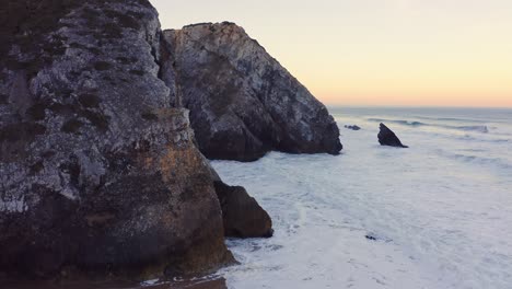 Aerial-Drone-View-of-Portugal-Atlantic-Coast-at-Lisbon,-a-Dramatic-Rugged-Rocky-Coastline-with-Waves-Crashing-and-Breaking-Against-Cliffs-at-Sunrise,-Sintra,-Europe