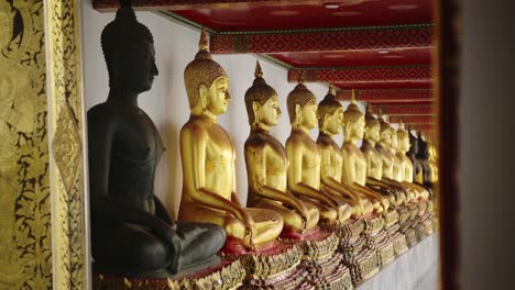 Gold-Buddha-Statue-in-Bangkok,-Thailand,-Lots-of-Buddhist-Statues-in-a-Row-at-Beautiful-Temple-for-Buddhism,-Line-of-Gold-Leaf-Buddhas-at-Wat-Pho