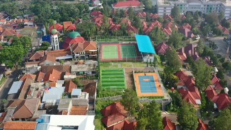 University-sports-complex-with-soccer-field-and-tennis-courts-in-Bandung-Indonesia,-aerial-top-down