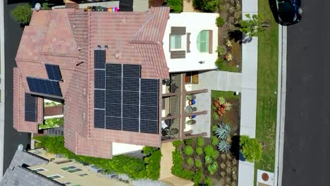 Solar-panels-on-a-residential-rooftop-provides-clean-energy---vertical-orientation-aerial-ascending-tilt-down