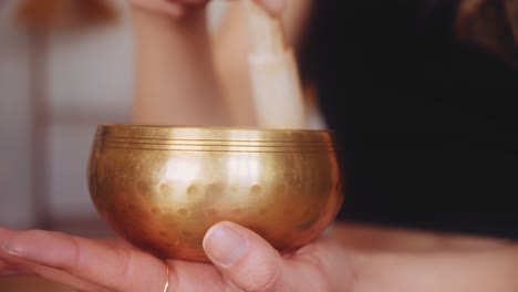 Close-up-gimbal-shot-of-feminine-hands-playing-Tibetan-singing-bowl