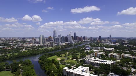 Aerial-view-over-the-Colorado-river,-towards-the-Austin-skyline,-sunny,-summer-day-in-Texas,-USA