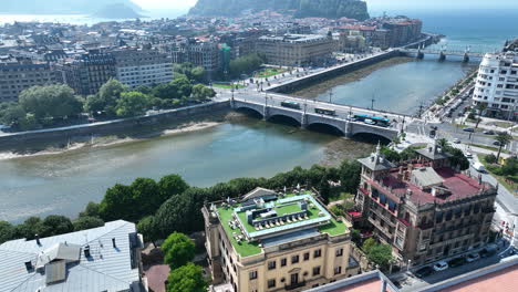 Aerial-drone-shot-of-the-Urumea-River-and-the-Santa-Catalina-Zubia-Bridge-arcing-around-to-reveal-the-Bay-of-Biscay-and-the-coastal-city-of-San-Sebastian,-Basque-Country
