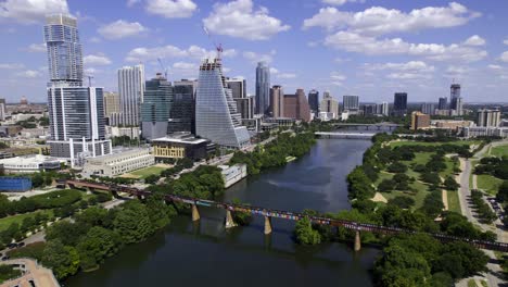 Aerial-view-of-the-river-and-downtown-Austin-skyscrapers,-in-sunny-Texas,-USA---tracking,-drone-shot