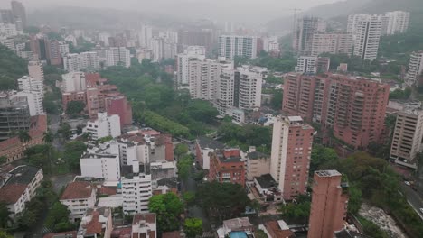 Wide-aerial-gimbal-down-shot-on-a-foggy-morning-in-downtown-Cali,-Colombia