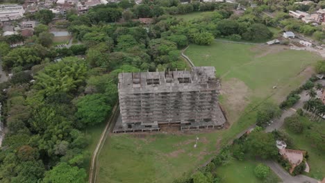 Wide-rotating-aerial-footage-of-an-abandoned-construction-project-next-to-a-golf-course-in-Cali,-Colombia