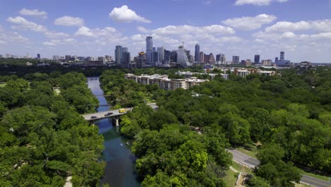 Aerial-view-overlooking-the-Zilker-park-with-Austin-city-background---tracking,-drone-shot