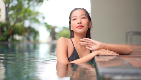 Close-up-of-an-attractive-woman-relaxing-along-the-side-of-a-posh-pool