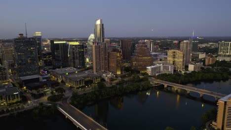 Aerial-view-away-from-downtown-Austin-and-over-bridges-on-the-river,-serene,-evening-in-Texas,-USA---pull-back,-drone-shot